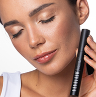 Model with closed eyes holding the mascara