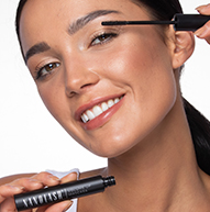 Smiling model applying the mascara